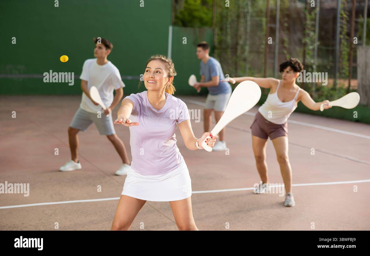 Femme servant le ballon pendant le jeu frontenis à l'extérieur Banque D'Images
