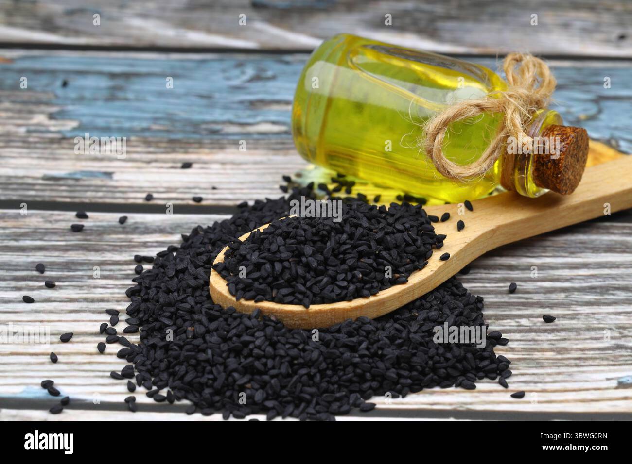 Graines de cumin noires et huile essentielle avec bol et pelle ou cuillère en bois. Nigella Sativa en bouteille de verre. La médecine biologique à base de plantes pour de nombreuses maladies Banque D'Images
