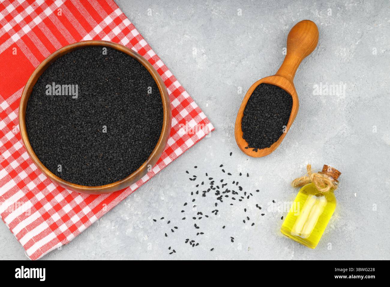 Graines de cumin noires et huile essentielle avec bol et pelle ou cuillère en bois. Nigella Sativa en bouteille de verre. La médecine biologique à base de plantes pour de nombreuses maladies Banque D'Images