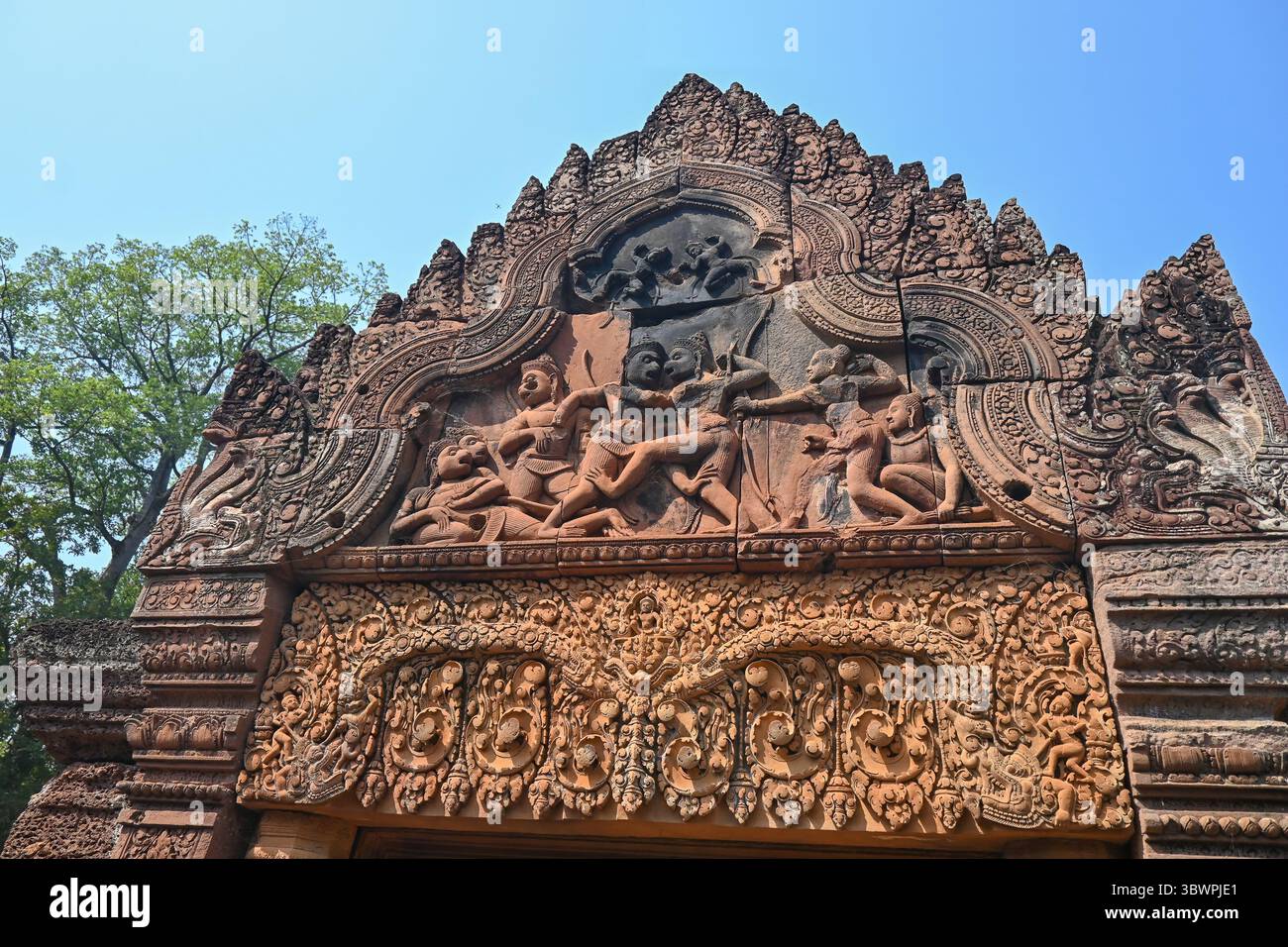 Gros plan d'une scène mythologique sculptée dans du grès rose sur un pignon de temple à Banteay Srei, Cambodge. Banque D'Images
