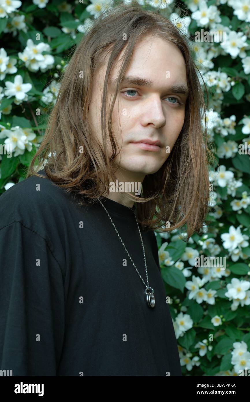 Une jeune personne aux cheveux longs se tient parmi les fleurs blanches brillantes dans la sérénité. Banque D'Images