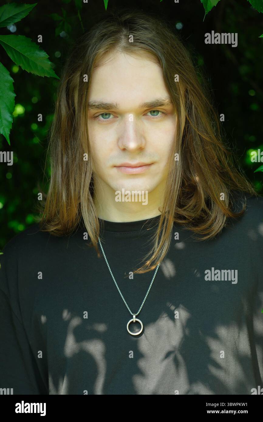 Un jeune adulte serein se dresse au milieu d'une végétation luxuriante, dégageant une confiance calme. Banque D'Images