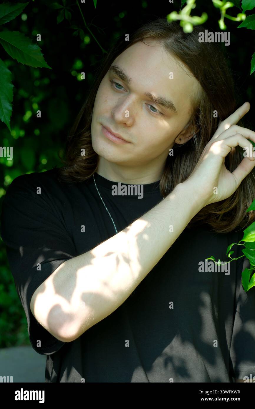 Une personne réfléchie interagit délicatement avec le feuillage vibrant tout en contemplant. Banque D'Images