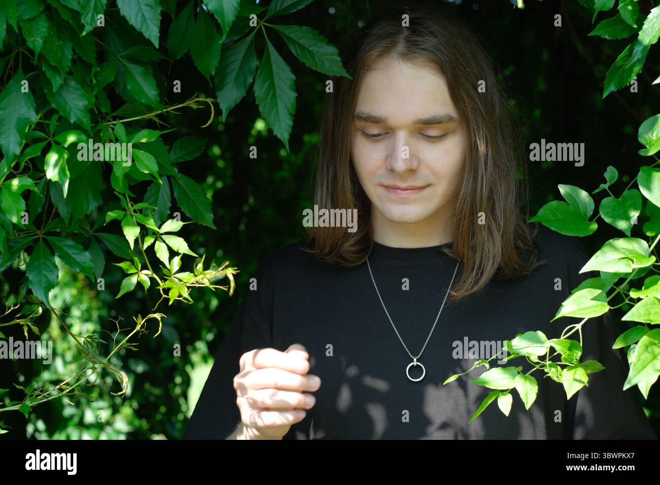 Une jeune personne se tient paisiblement entourée d'un feuillage riche, jouissant de la tranquillité. Banque D'Images