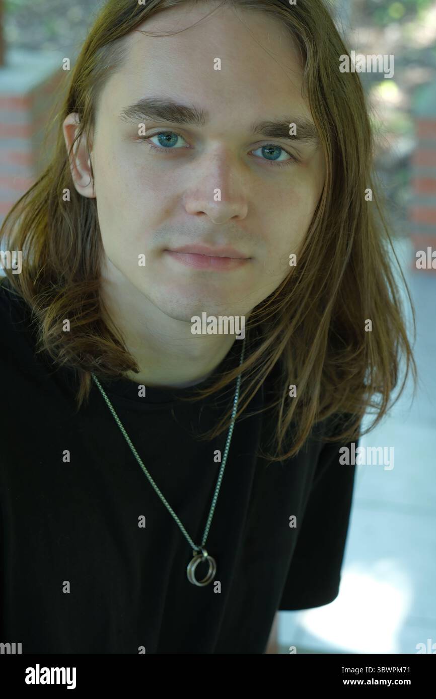 Un jeune homme serein profite d'un moment paisible à l'extérieur sous la lumière douce du soleil. Banque D'Images