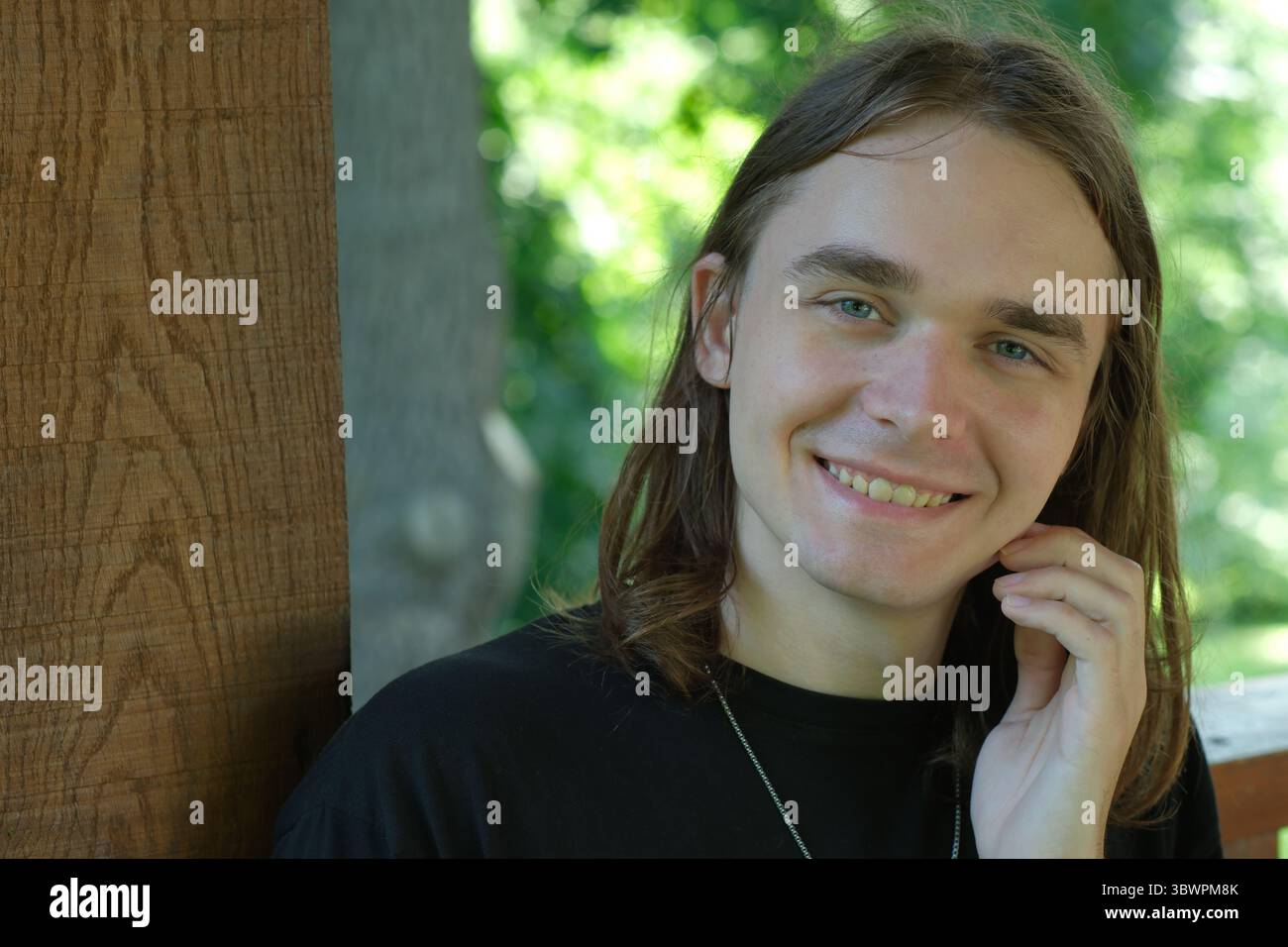 Un jeune homme joyeux apprécie la chaleur de la nature tout en souriant doucement. Banque D'Images