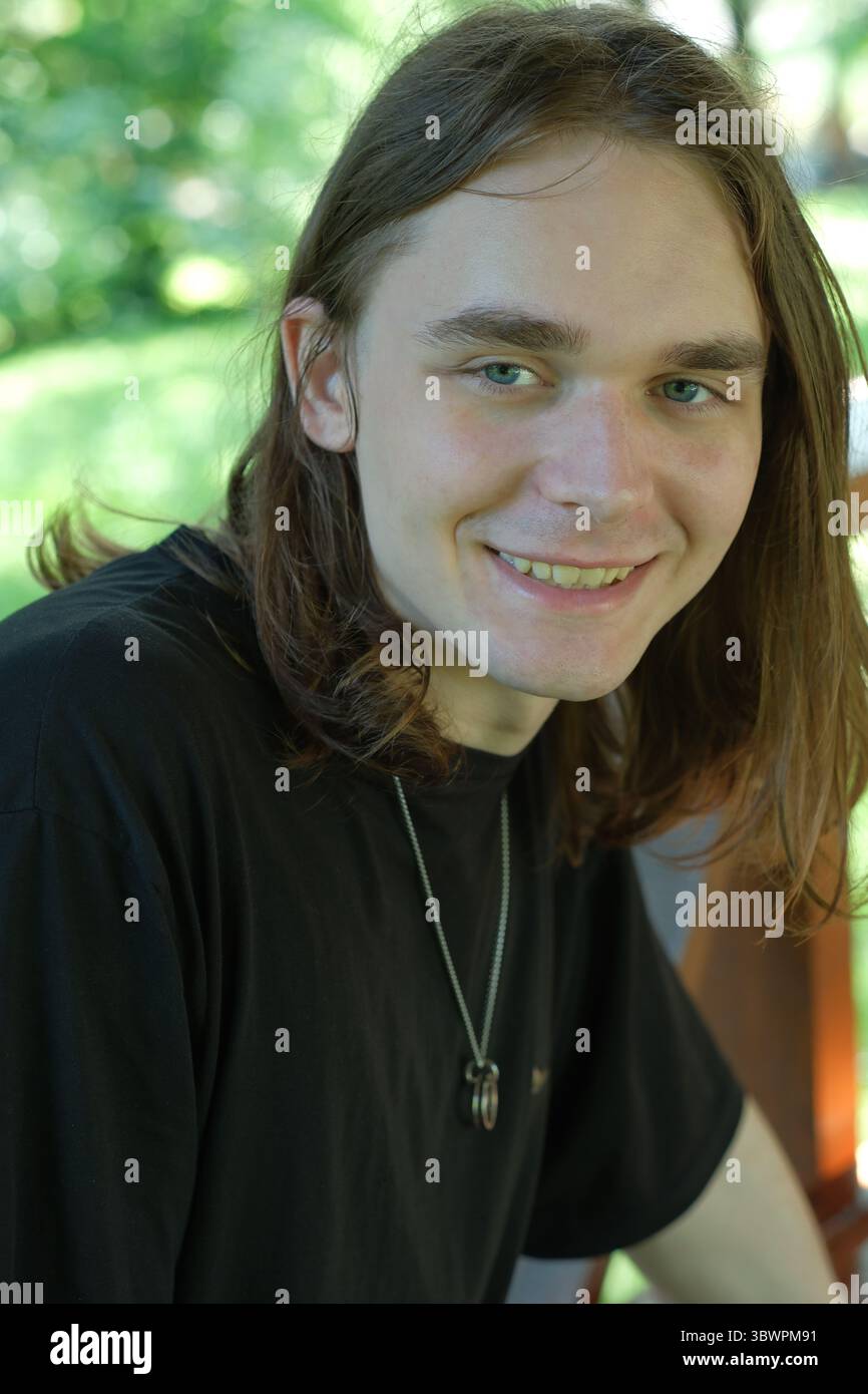 Un jeune homme joyeux profite de la lumière du soleil, entouré de verdure luxuriante. Banque D'Images