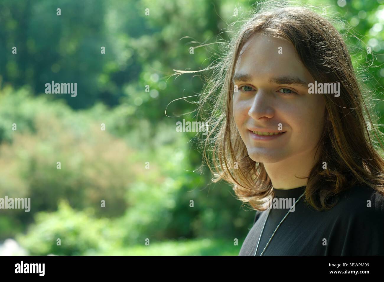 Une jeune personne sourit doucement dans une nature vibrante, profitant de la tranquillité. Banque D'Images