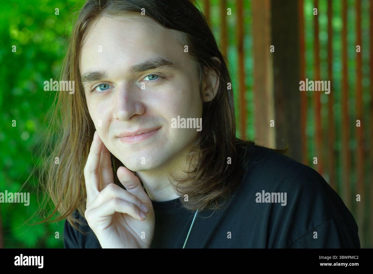 Un jeune homme aux cheveux longs profite d'un moment paisible entouré par la nature. Banque D'Images