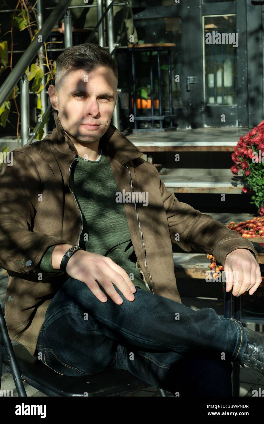 Dans un jardin animé, un jeune homme se détend sous la chaleur du soleil. Banque D'Images