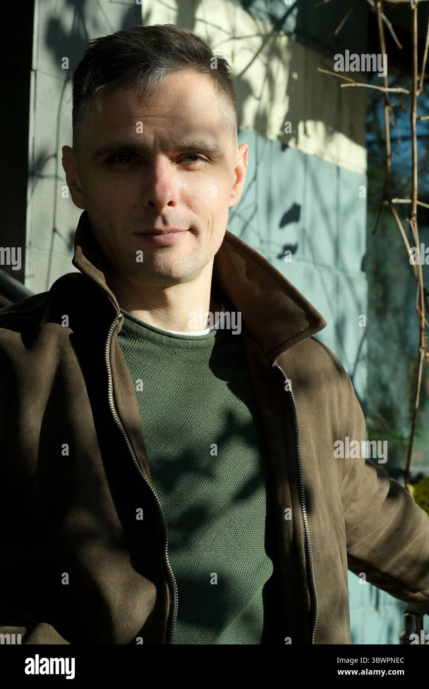 Un homme confiant pose à l'extérieur avec une lumière naturelle charmante soulignant ses traits. Banque D'Images