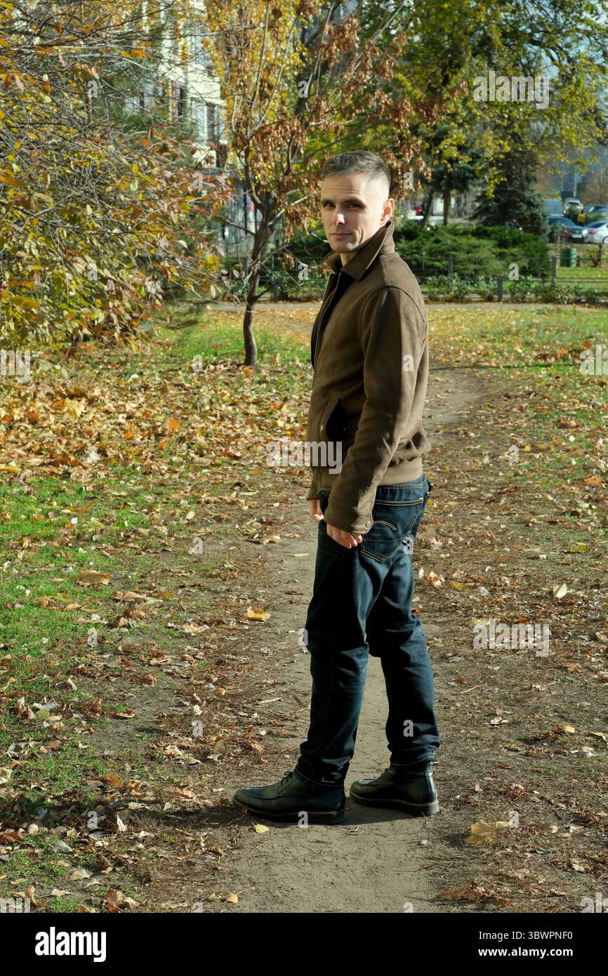 Un jeune homme se promène le long d'un chemin sinueux entouré de feuilles d'automne colorées. Banque D'Images