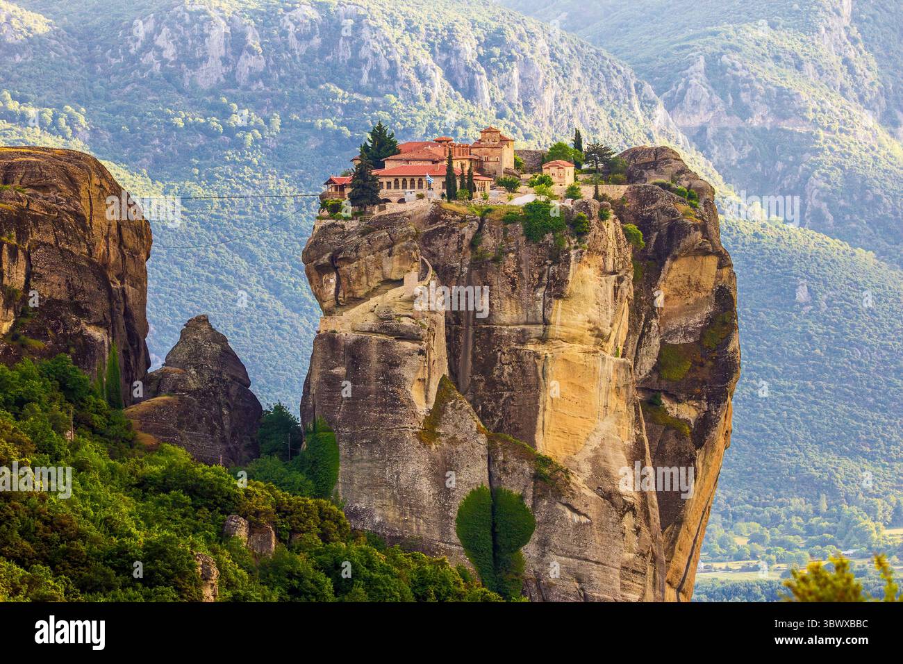 Vue estivale de l'après-midi sur le paysage des Météores en Grèce, avec le monastère de la Sainte Trinité perché au sommet d'une spectaculaire formation rocheuse monolithique Banque D'Images