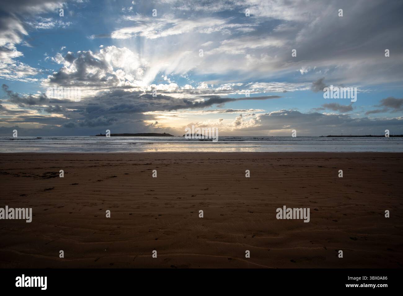Coucher de soleil sur les vastes plages d’Essaouira avec un ciel bleu, des nuages blancs et des vagues s’écrasant sur le rivage au Maroc Banque D'Images