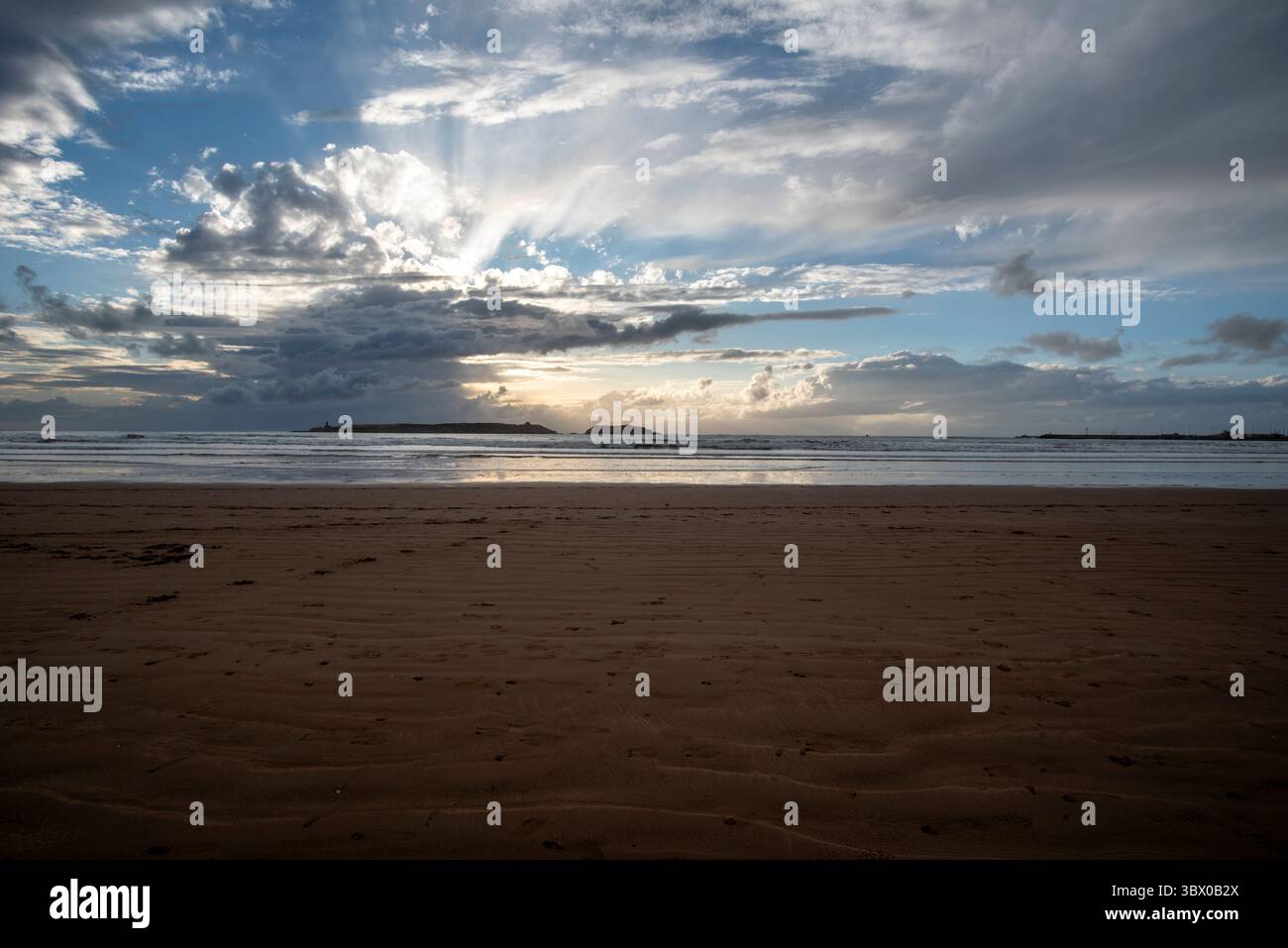 Coucher de soleil sur les vastes plages d’Essaouira avec un ciel bleu, des nuages blancs et des vagues s’écrasant sur le rivage au Maroc Banque D'Images