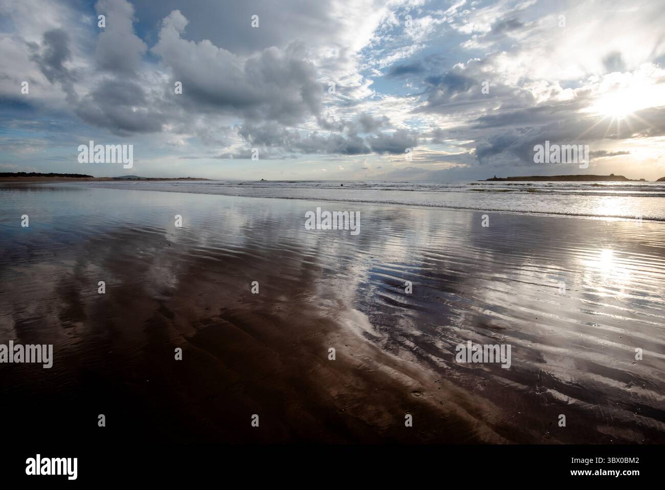 Coucher de soleil sur les vastes plages d’Essaouira avec un ciel bleu, des nuages blancs et des vagues s’écrasant sur le rivage au Maroc Banque D'Images