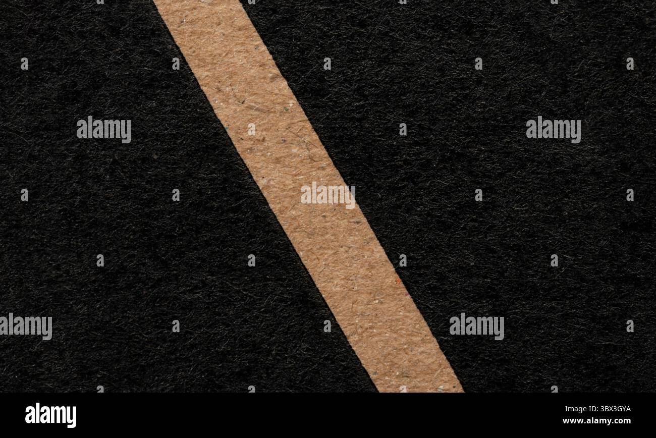 Le matériau noir présente une ligne beige proéminente, créant un contraste visuel saisissant et une texture dans une composition minimaliste. Banque D'Images