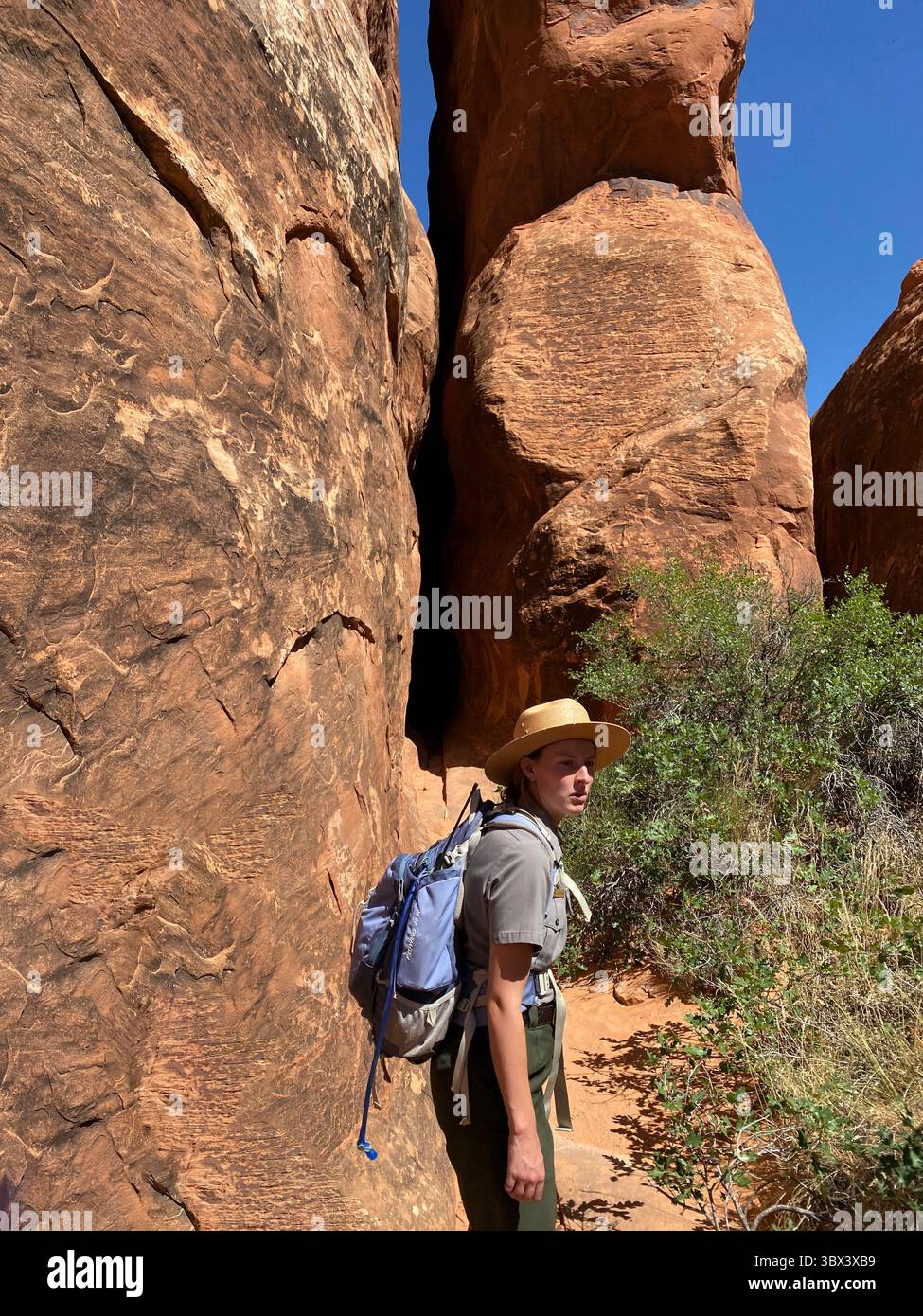 Un Ranger du parc national menant une visite dans un canyon à fente, en grès rouge, dans le parc national des Arches, Moab, Utah, par une chaude journée d'été - Image de stock capturée avec un smartphone