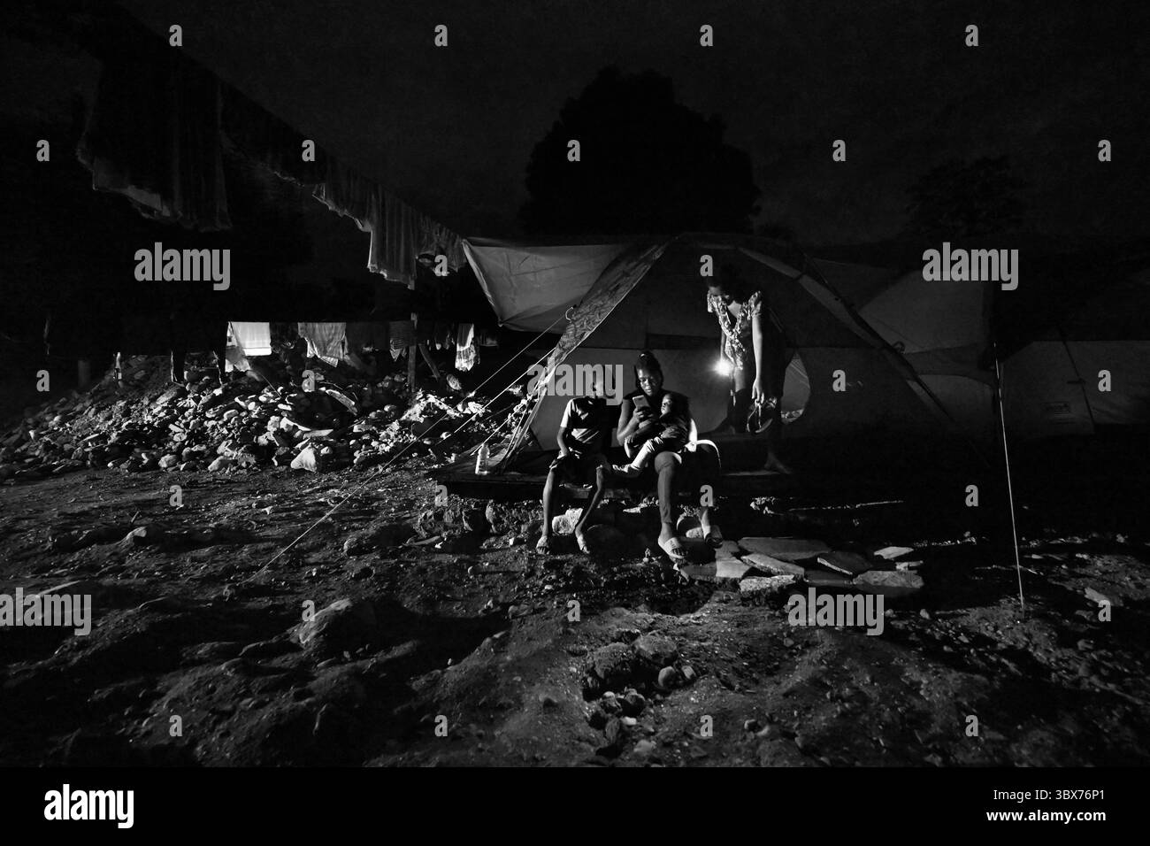 26 août 2021, Maniche, Haïti : S’il y a de la vie, il y a hopeâ€™ â€“ Chrislome Lorbensky, survivant. Chrislome Lorbensky et son épouse Altema Rosenine avec leur fils de 11 mois Adonia Ande Lorbensky, surnommé ton ton, font face aux conséquences d’un ouragan massif à Maniche, Haïti le 26 août 2021. Elle pleure en regardant des photos sur son téléphone de la fille qu'elle pleure... ils ont perdu leur fille de 3 ans dans le séisme et se sont accrochés à leur bébé survivant avec un plâtre sur sa jambe cassée. Il a été retrouvé sous le cadavre de son oncle sur ce terrain où ils s'efforcent maintenant de reconstruire. Ils devaient qui Banque D'Images