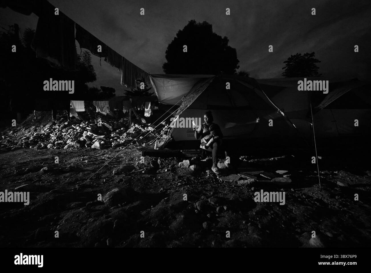 26 août 2021, Maniche, Haïti : S’il y a de la vie, il y a hopeâ€™ â€“ Chrislome Lorbensky, survivant. Chrislome Lorbensky et son épouse Altema Rosenine avec leur fils de 11 mois Adonia Ande Lorbensky, surnommé ton ton, font face aux conséquences d’un ouragan massif à Maniche, Haïti le 26 août 2021. Elle pleure en regardant des photos sur son téléphone de la fille Adonia Ande Lorbensky qu'elle pleure... ils ont perdu leur fille de 3 ans dans le séisme et s'accrochent à leur bébé survivant avec un plâtre sur sa jambe cassée. Il a été retrouvé sous le cadavre de son oncle sur ce terrain où ils s'efforcent de ne pas le faire Banque D'Images