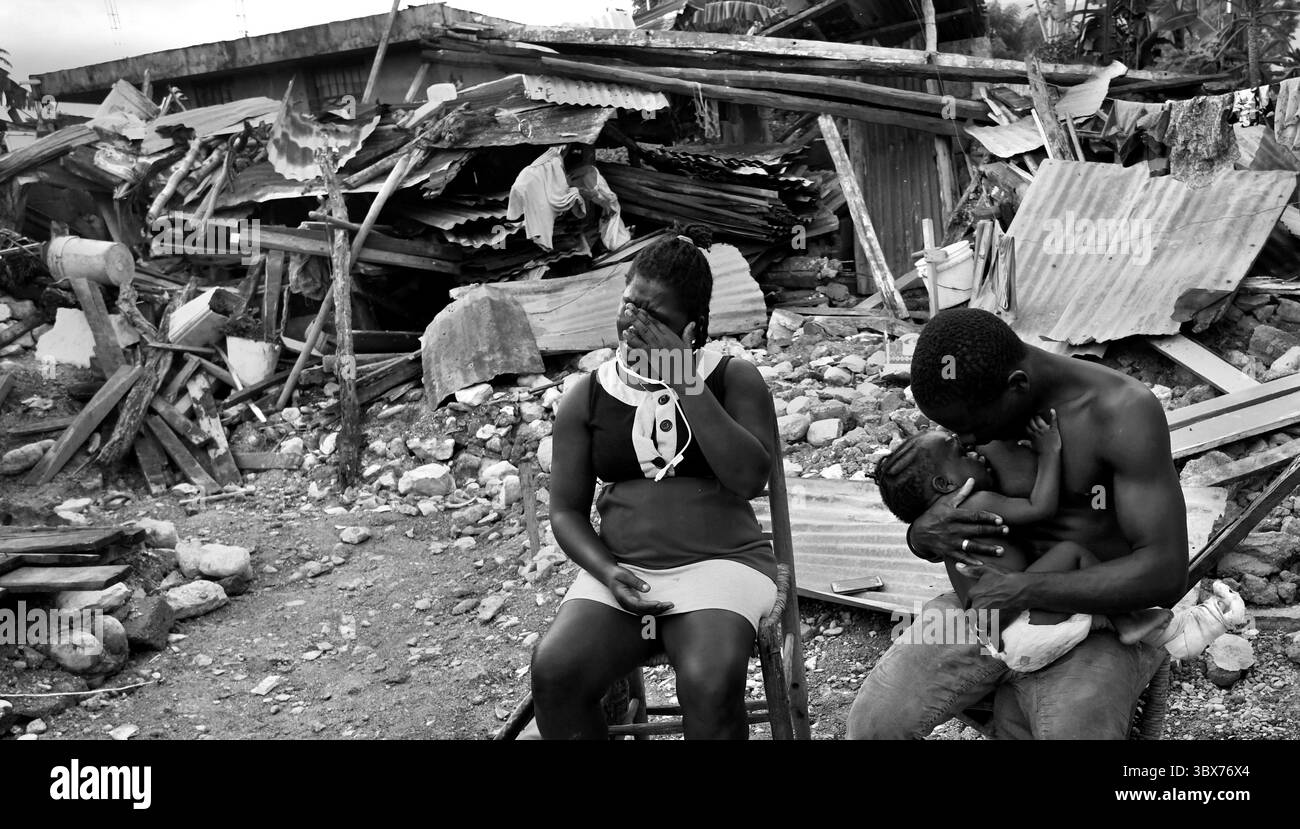 27 août 2021, Maniche, Haïti : S’il y a de la vie, il y a hopeâ€™ â€“ Chrislome Lorbensky, survivant. Chrislome Lorbensky et son épouse Altema Rosenine avec leur fils de 11 mois Adonia Ande Lorbensky, surnommé ton ton, font face aux conséquences d’un ouragan massif à Maniche, Haïti le 27 août 2021. Rosenine pleure pendant une interview alors qu'elle parle d'Adonia Ande Lorbensky, la fille qu'elle pleure, ..ils ont perdu leur fille de 3 ans dans le séisme et s'accrochent à leur bébé survivant avec un plâtre sur sa jambe cassée. Il a été retrouvé sous le cadavre de son oncle sur ce terrain où ils s'efforcent de le faire Banque D'Images