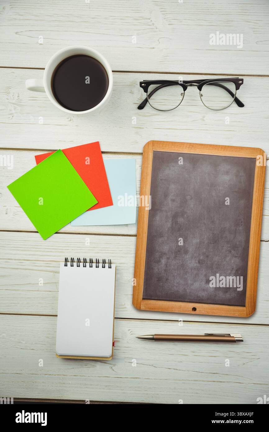 L'espace de travail de conception plate montre tasse à café, verres, notes adhésives, tableau noir sur le dessus de table peint Banque D'Images