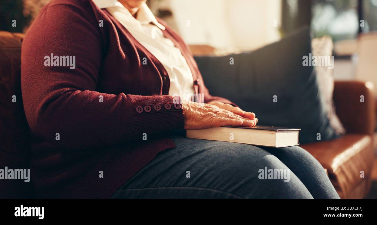 Prier, mains et Bible avec la vieille femme sur le canapé pour le culte, la gratitude et la paix. Religion, connexion spirituelle et foi avec la personne et le livre Banque D'Images