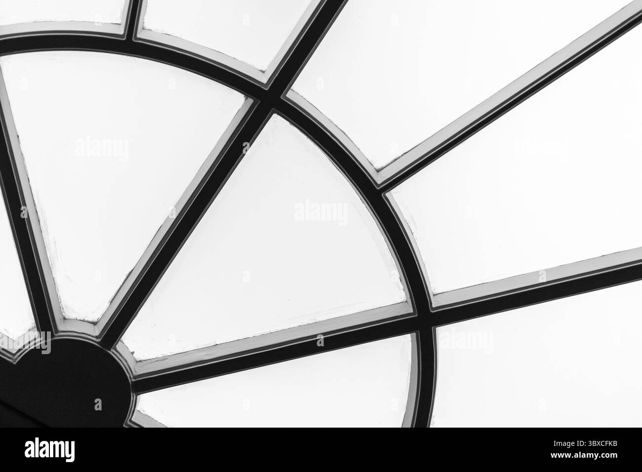 Photo en noir et blanc d'un détail géométrique de fenêtre avec des lignes et des formes qui se croisent, créant une composition abstraite Banque D'Images