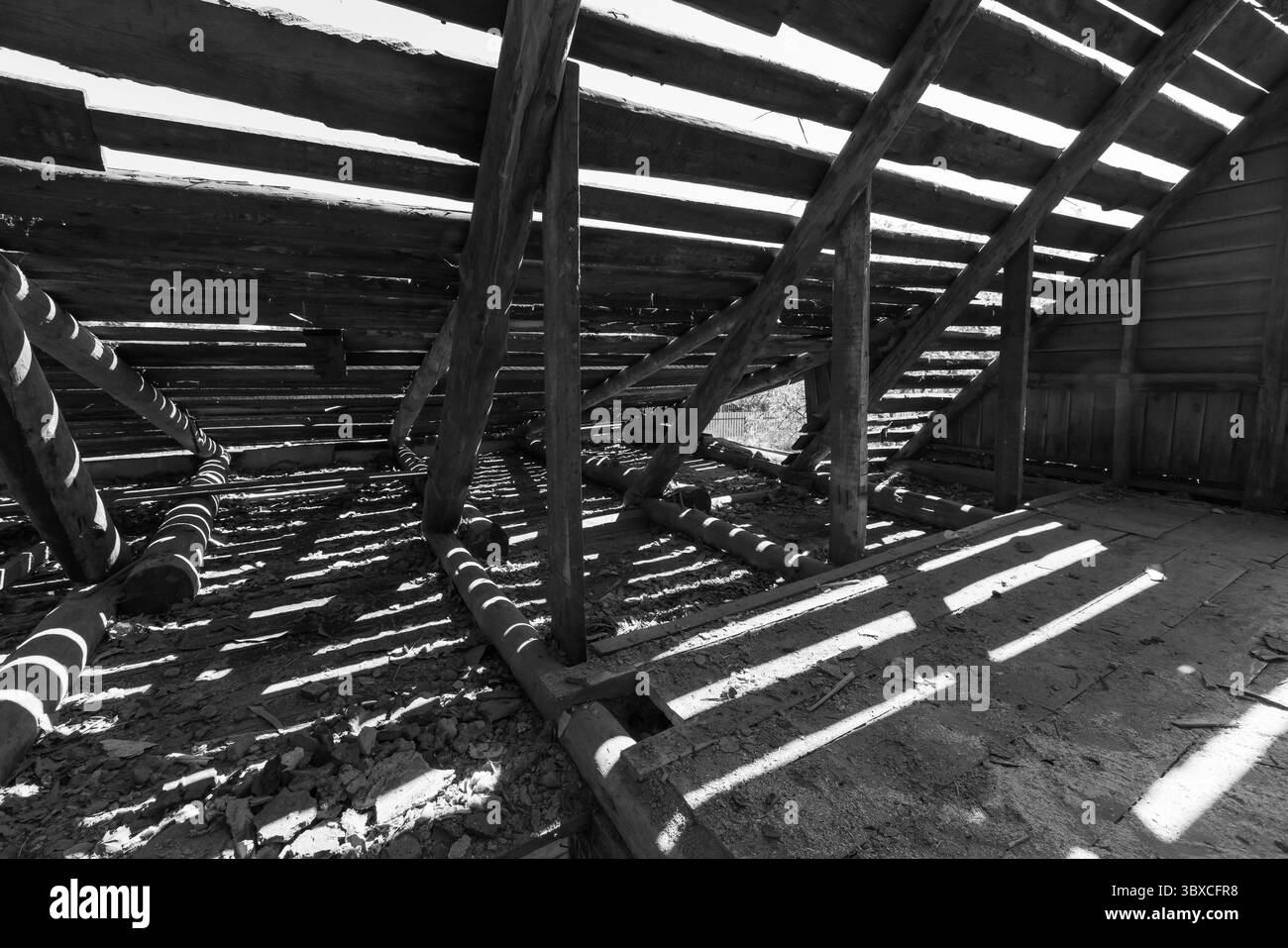Vue intérieure sombre avec structure en bois présentant des poutres apparentes avec la lumière du soleil créant des motifs uniques. Photogra abstrait de fond noir et blanc Banque D'Images
