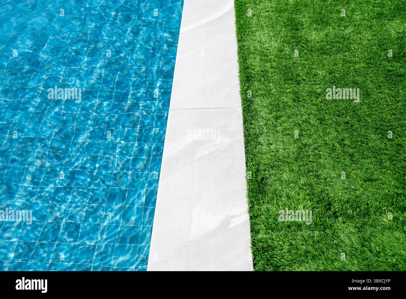 Piscine d'une maison de luxe avec tuiles blanches autour et herbe verte et eau bleu turquoise transparent clair. Immobilier, gestion immobilière Banque D'Images