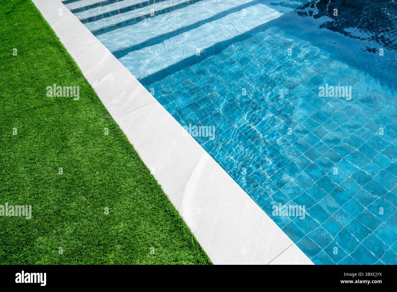 Piscine d'une maison de luxe avec tuiles blanches autour et herbe verte et eau bleu turquoise transparent clair. Immobilier, gestion immobilière Banque D'Images