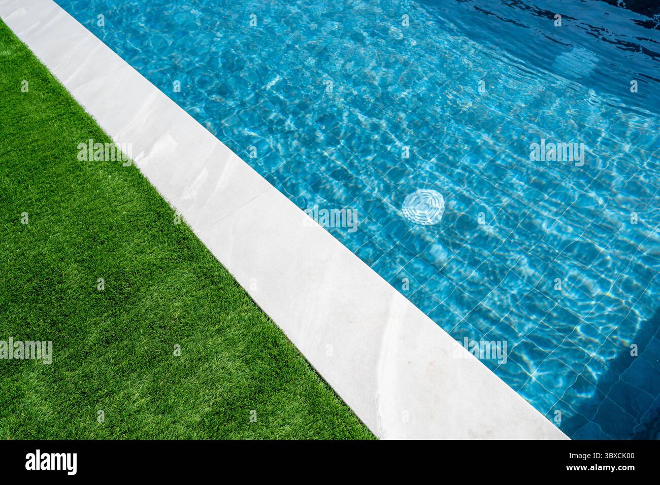 Piscine d'une maison de luxe avec tuiles blanches autour et herbe verte et eau bleu turquoise transparent clair. Immobilier, gestion immobilière Banque D'Images