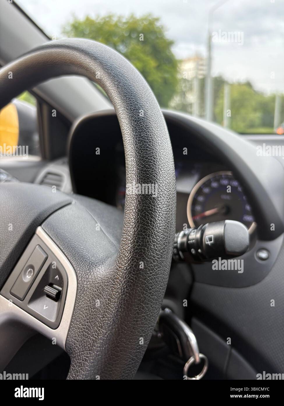 Une photo verticale d'un volant de voiture sans mains en conduisant dans la ville. Gros plan d'un volant de voiture pendant la journée. Banque D'Images