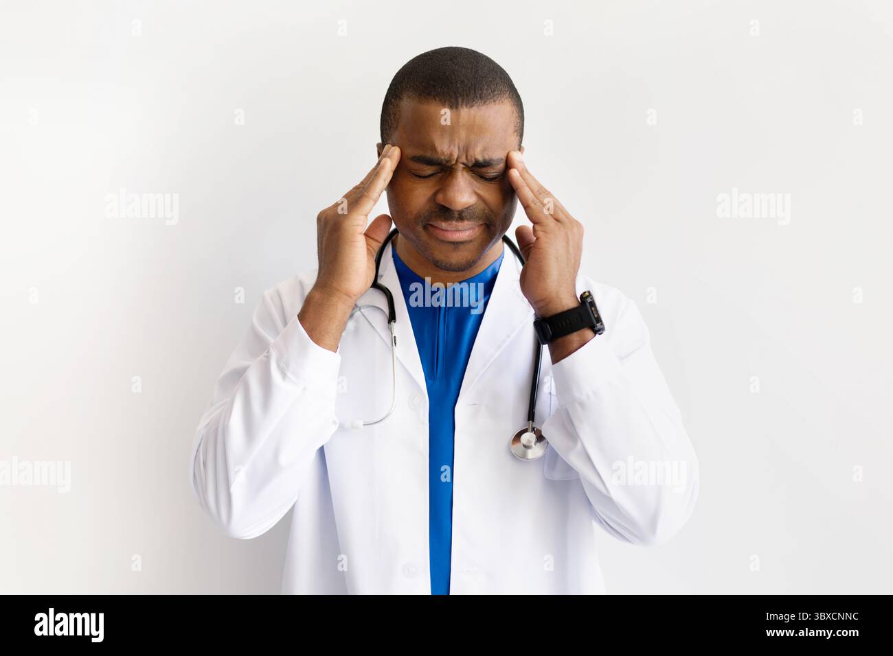 Médecin noir stressé touchant les tempes, souffrant de maux de tête, yeux fermés dans la douleur Banque D'Images