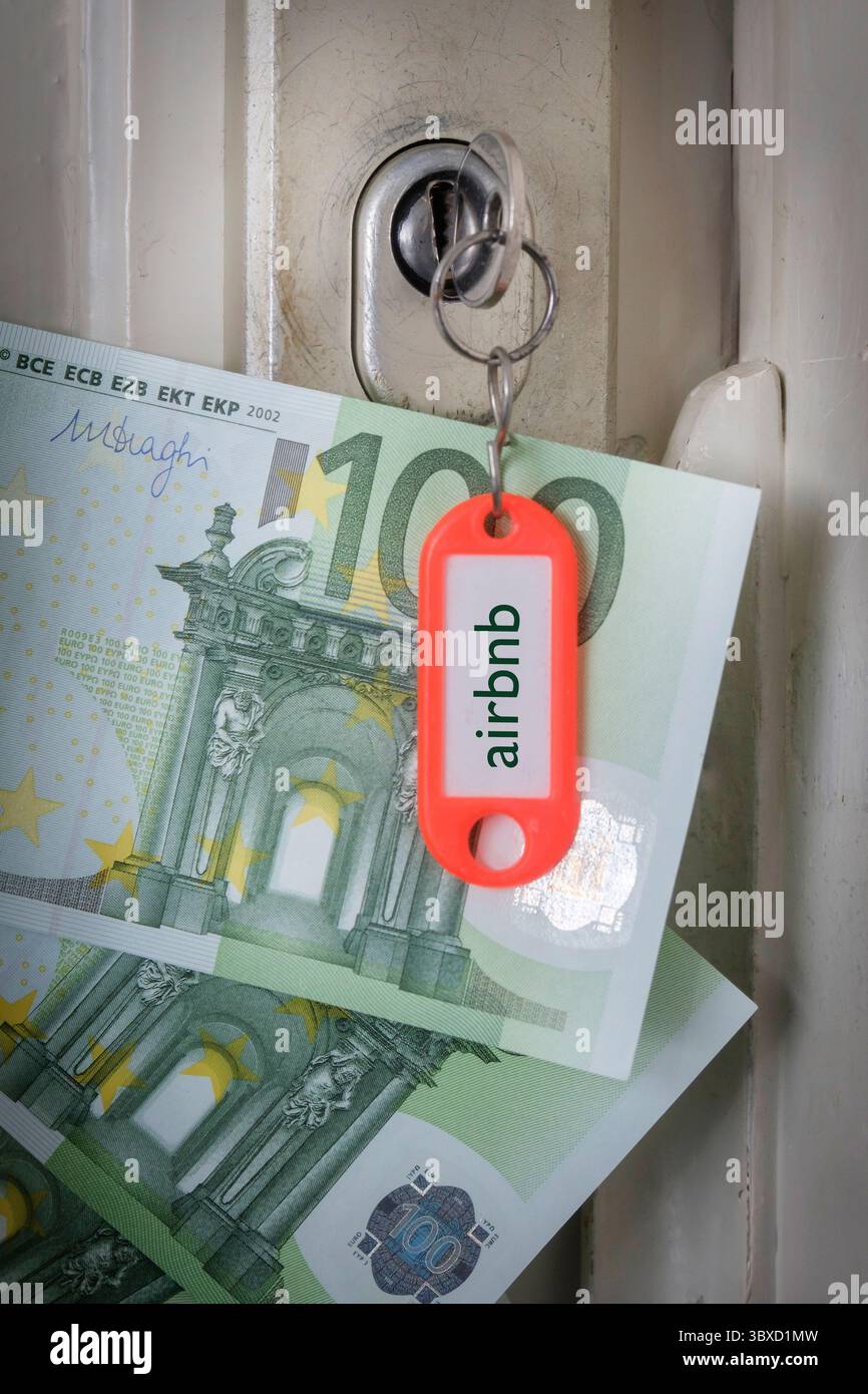 Une clé est coincée dans la serrure de la porte, les mots Airbnb sont gravés sur l'étiquette et il y a des billets en euros à côté. Banque D'Images