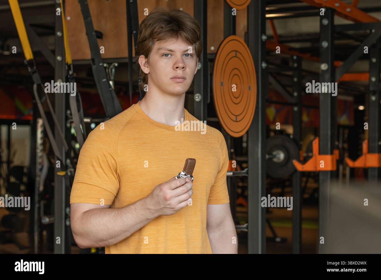 Homme sportif mangeant une barre énergétique. Encas musclés pour sportifs barre protéinée tout en se reposant après une séance d'entraînement au gymnase ou au centre de fitness. Banque D'Images
