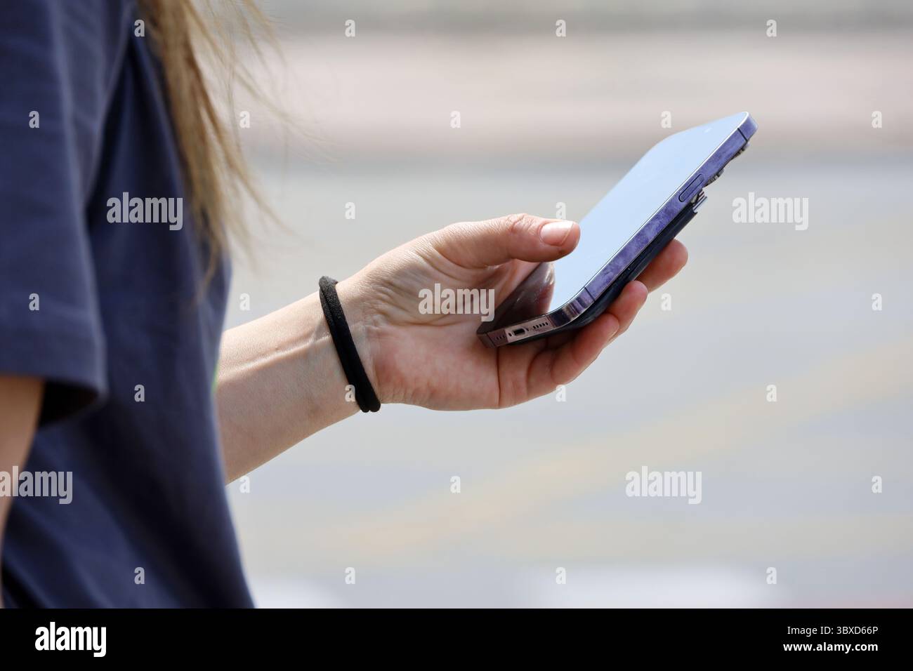 Smartphone dans la main féminine, fille utilisant le téléphone portable sur la rue de la ville à l'été Banque D'Images