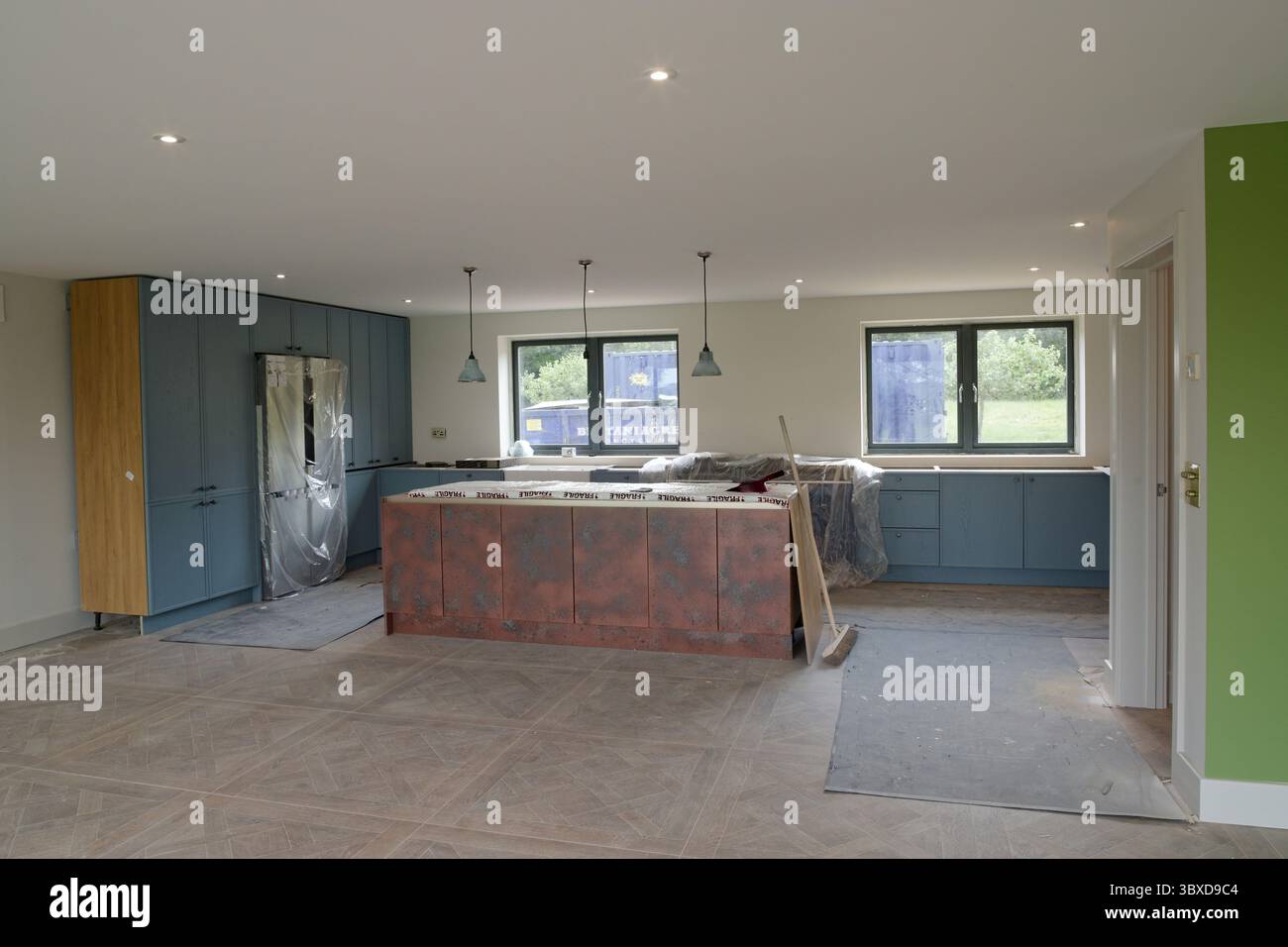 Une nouvelle cuisine en cours d'installation. Unités de cuisine et une unité d'îlot de cuisine avec trois lumières au-dessus. Nouveau plancher et un nouveau réfrigérateur. Banque D'Images