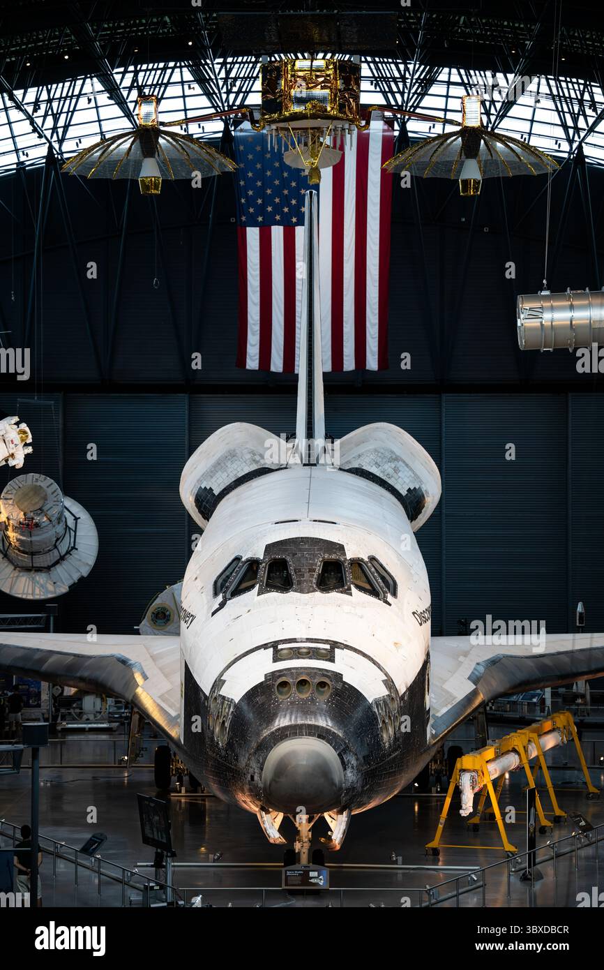 Exposition découverte de la navette spatiale au Steven F Udvar-Hazy Center à Chantilly Virginie | CHANTILLY, Virginie — les visiteurs du musée se tiennent sous le nez de la navette spatiale Discovery dans cette vue large du hangar spatial James S. McDonnell, où l'orbiteur est suspendu le long d'un vaisseau spatial Gemini et d'une combinaison spatiale près du toit couvert du Steven F. Udvar-Hazy Center. Discovery est la navette la plus utilisée de la NASA, accomplissant 39 missions entre 1984 et 2011. Banque D'Images
