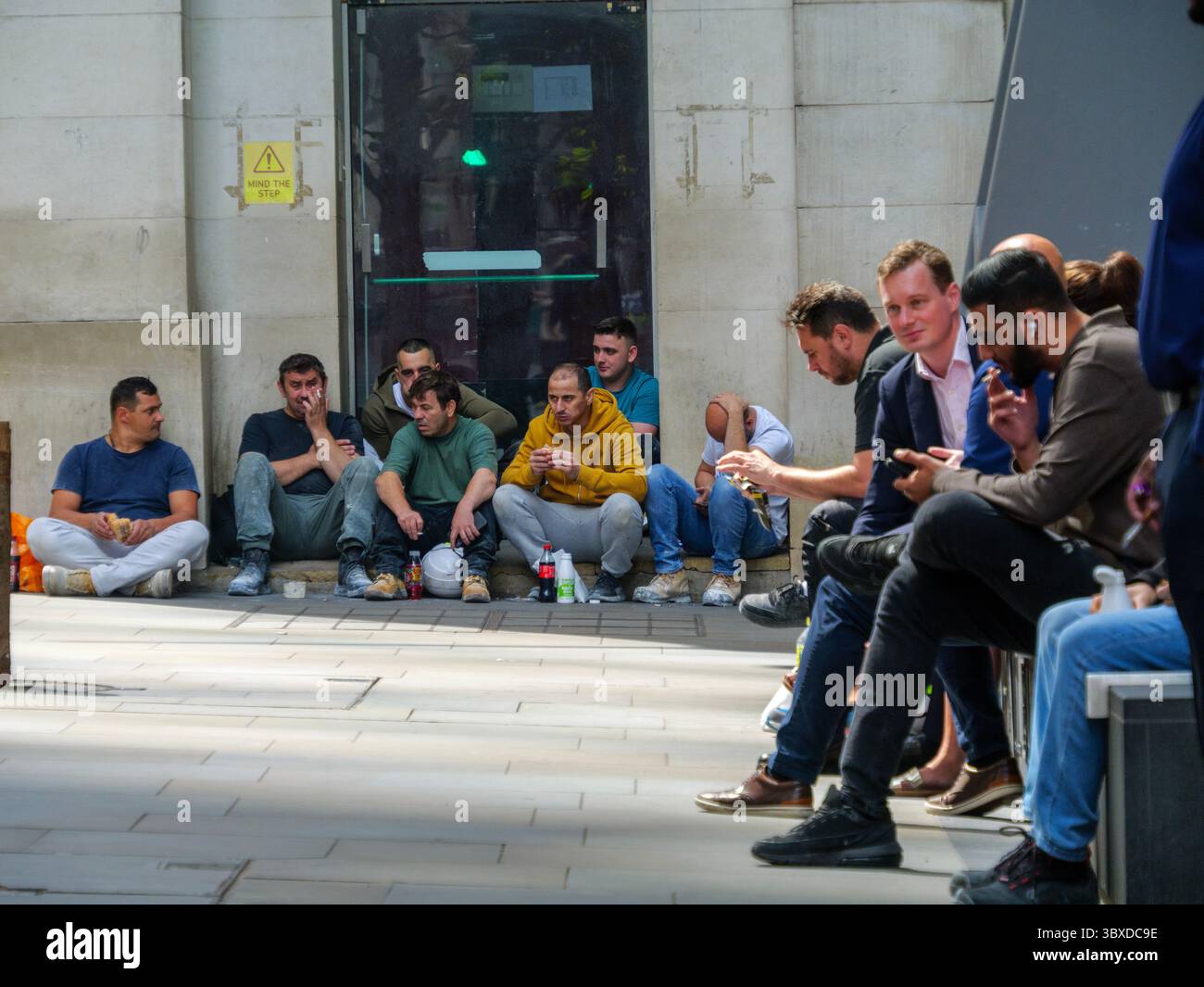 Les cols bleus et les cols blancs partagent une pause déjeuner dans la ville de Londres, au Royaume-Uni, les travailleurs de la construction s'assoient sur les marches tandis que le personnel de bureau se détendent sur des sièges désignés, capturant la main-d'œuvre diversifiée qui alimente le cœur financier et commercial de la capitale Banque D'Images