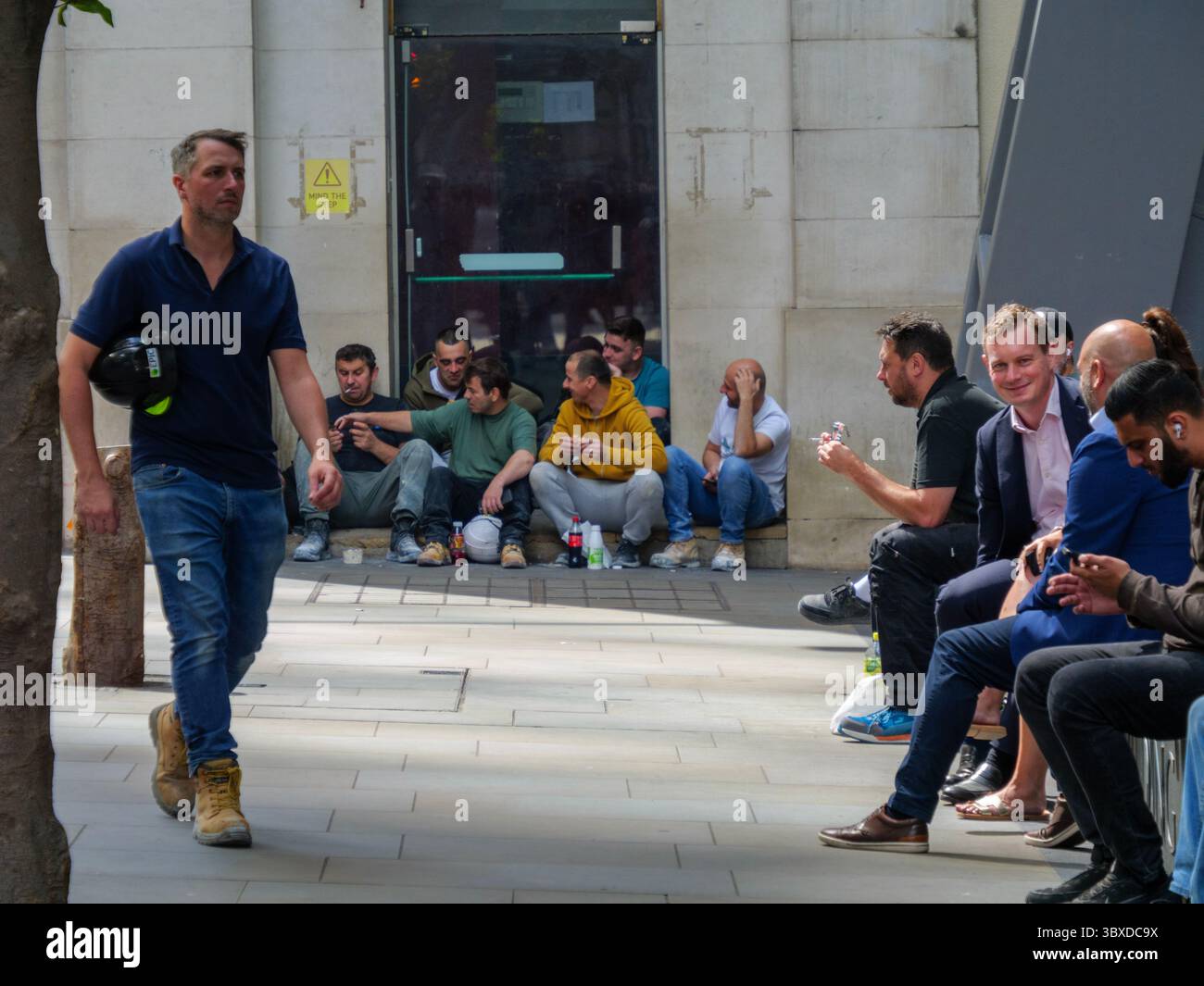 Les cols bleus et les cols blancs partagent une pause déjeuner dans la ville de Londres, au Royaume-Uni, les travailleurs de la construction s'assoient sur les marches tandis que le personnel de bureau se détendent sur des sièges désignés, capturant la main-d'œuvre diversifiée qui alimente le cœur financier et commercial de la capitale Banque D'Images