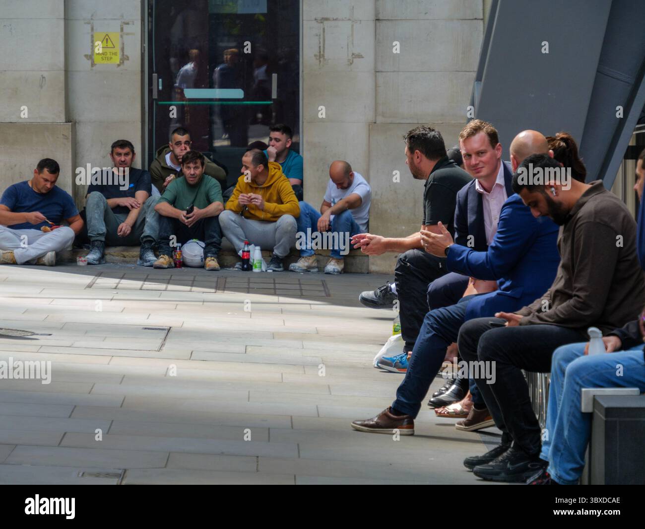 Les cols bleus et les cols blancs partagent une pause déjeuner dans la ville de Londres, au Royaume-Uni, les travailleurs de la construction s'assoient sur les marches tandis que le personnel de bureau se détendent sur des sièges désignés, capturant la main-d'œuvre diversifiée qui alimente le cœur financier et commercial de la capitale Banque D'Images