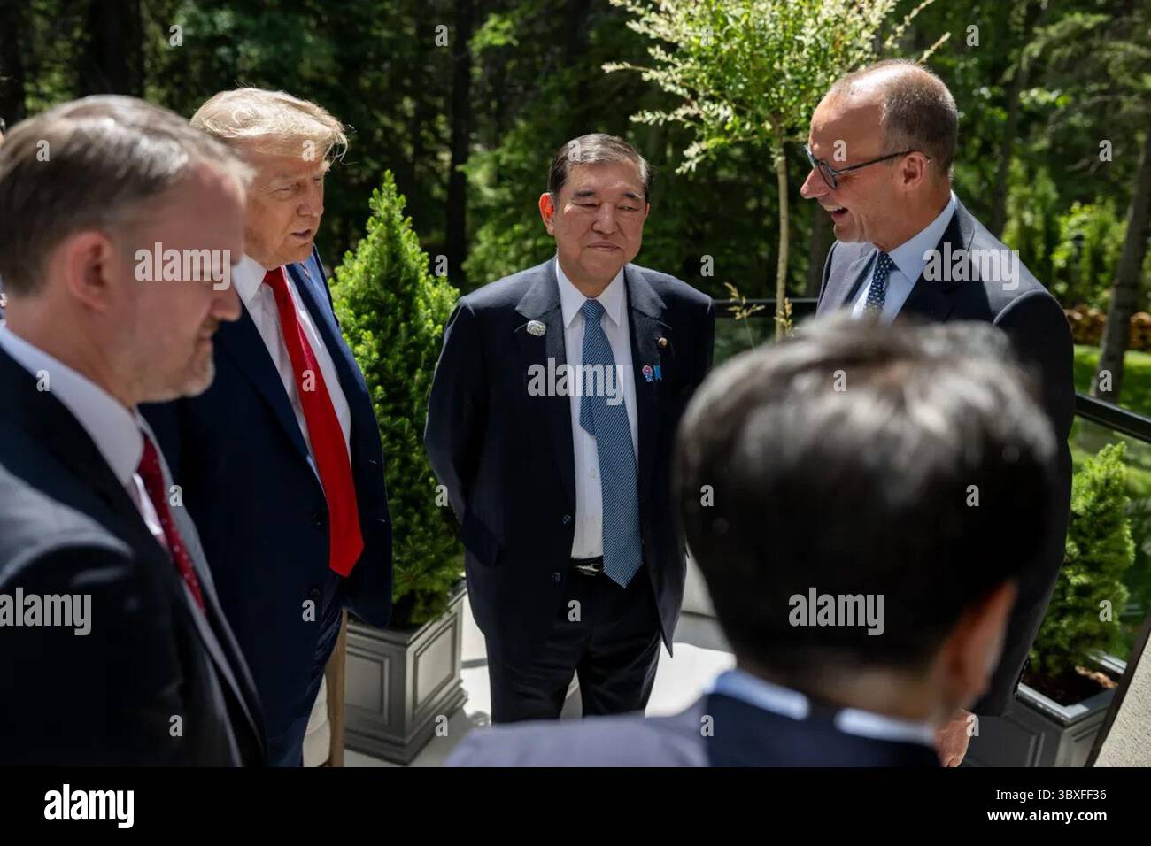 Les dirigeants mondiaux et les hauts fonctionnaires engagent des conversations à l’extérieur au milieu d’une végétation luxuriante et de plantes en pot lors du Sommet du G7 à Kananaskis, Alberta, Canada, le 16 juin 2025. Le président Donald J. Trump est vu parmi les délégués, participant à des discussions de haut niveau sur le commerce mondial, la sécurité et la coopération économique. Banque D'Images