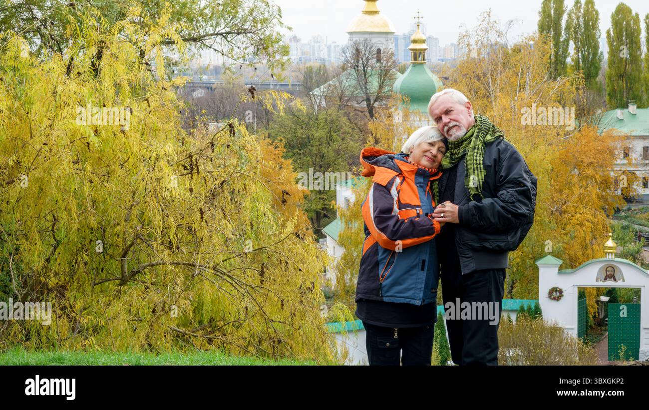 Un vieux couple optimiste aux cheveux gris dans l'amour homme et femme sur fond de plantes d'automne jaunes et d'églises chrétiennes orthodoxes Banque D'Images