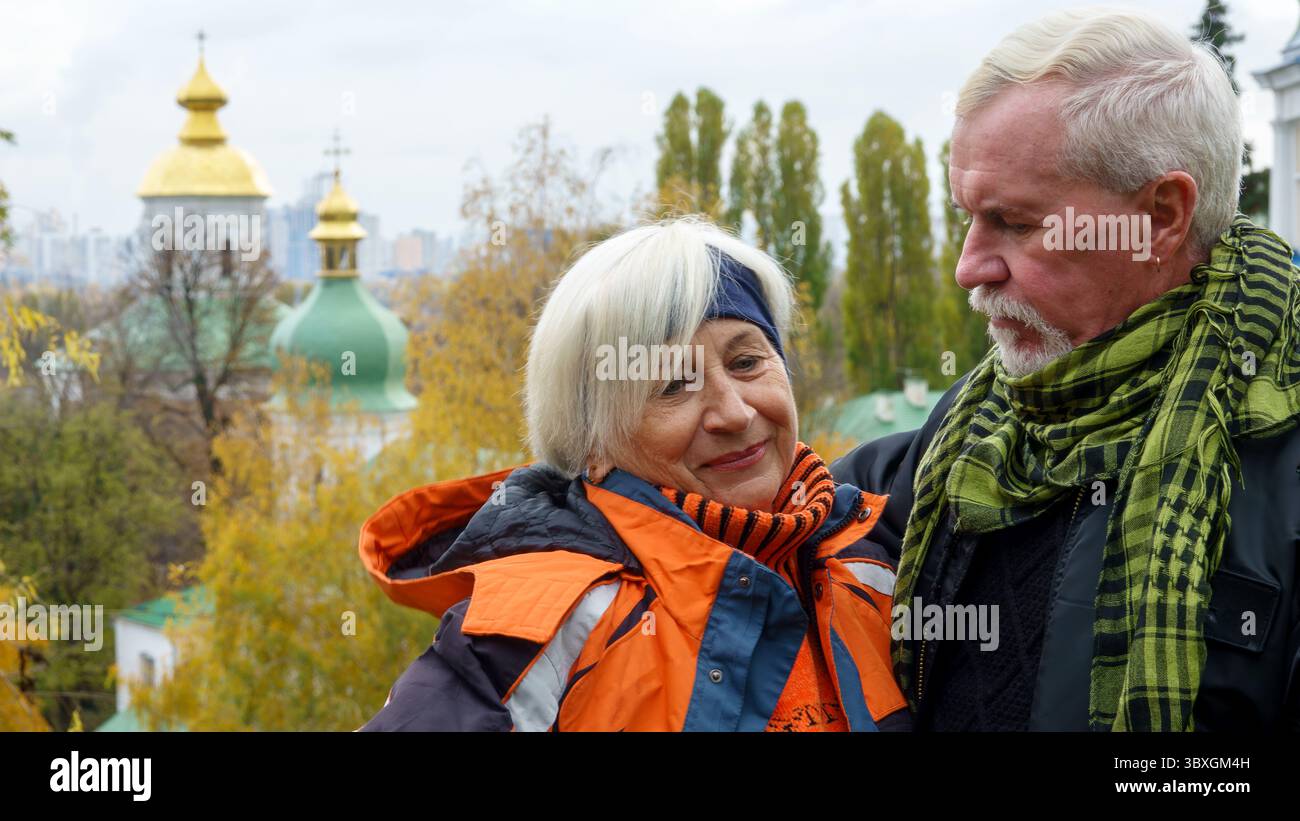 Un vieux couple optimiste aux cheveux gris dans l'amour homme et femme sur fond de plantes d'automne jaunes et d'églises chrétiennes orthodoxes Banque D'Images