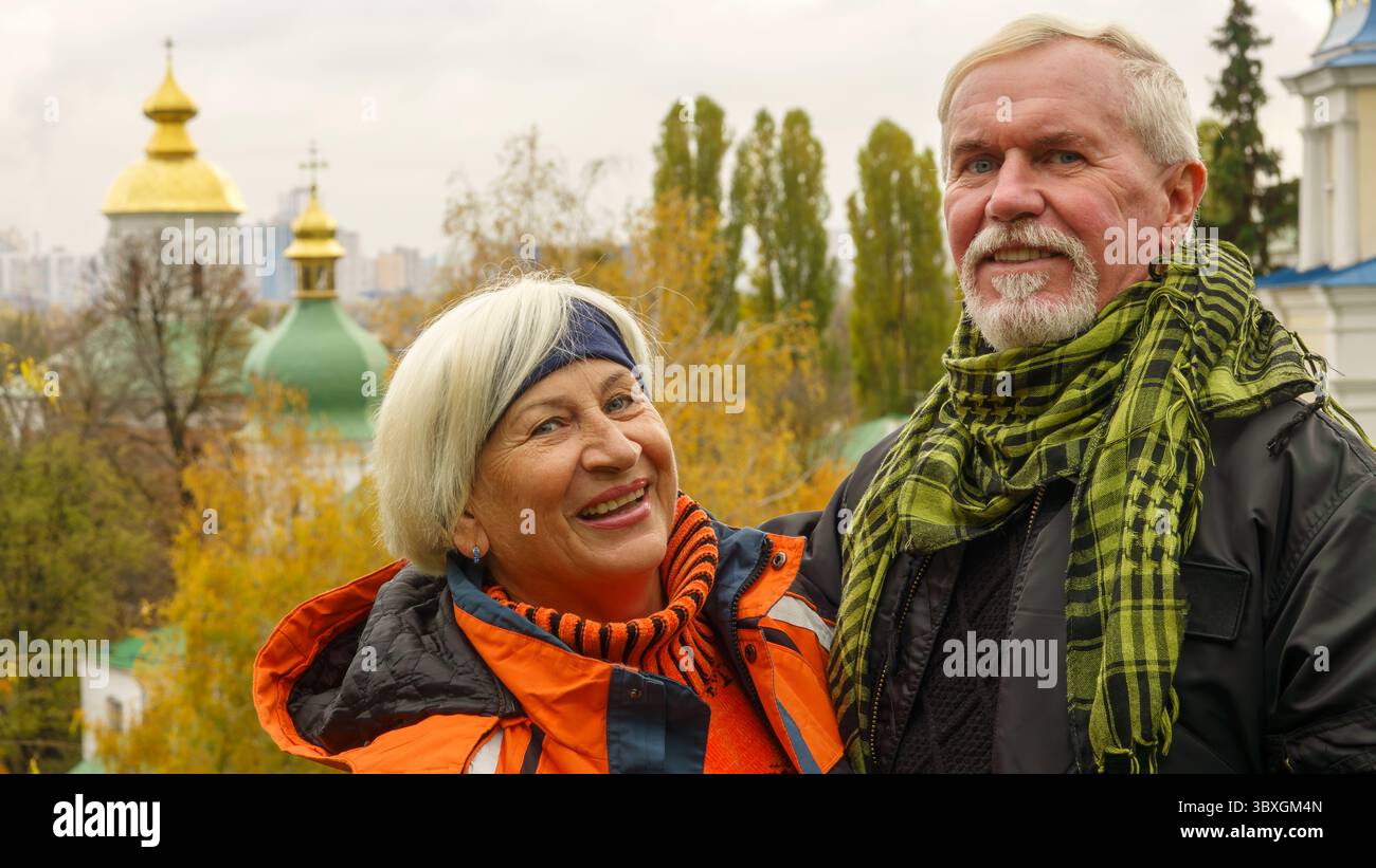 Un vieux couple optimiste aux cheveux gris dans l'amour homme et femme sur fond de plantes d'automne jaunes et d'églises chrétiennes orthodoxes Banque D'Images
