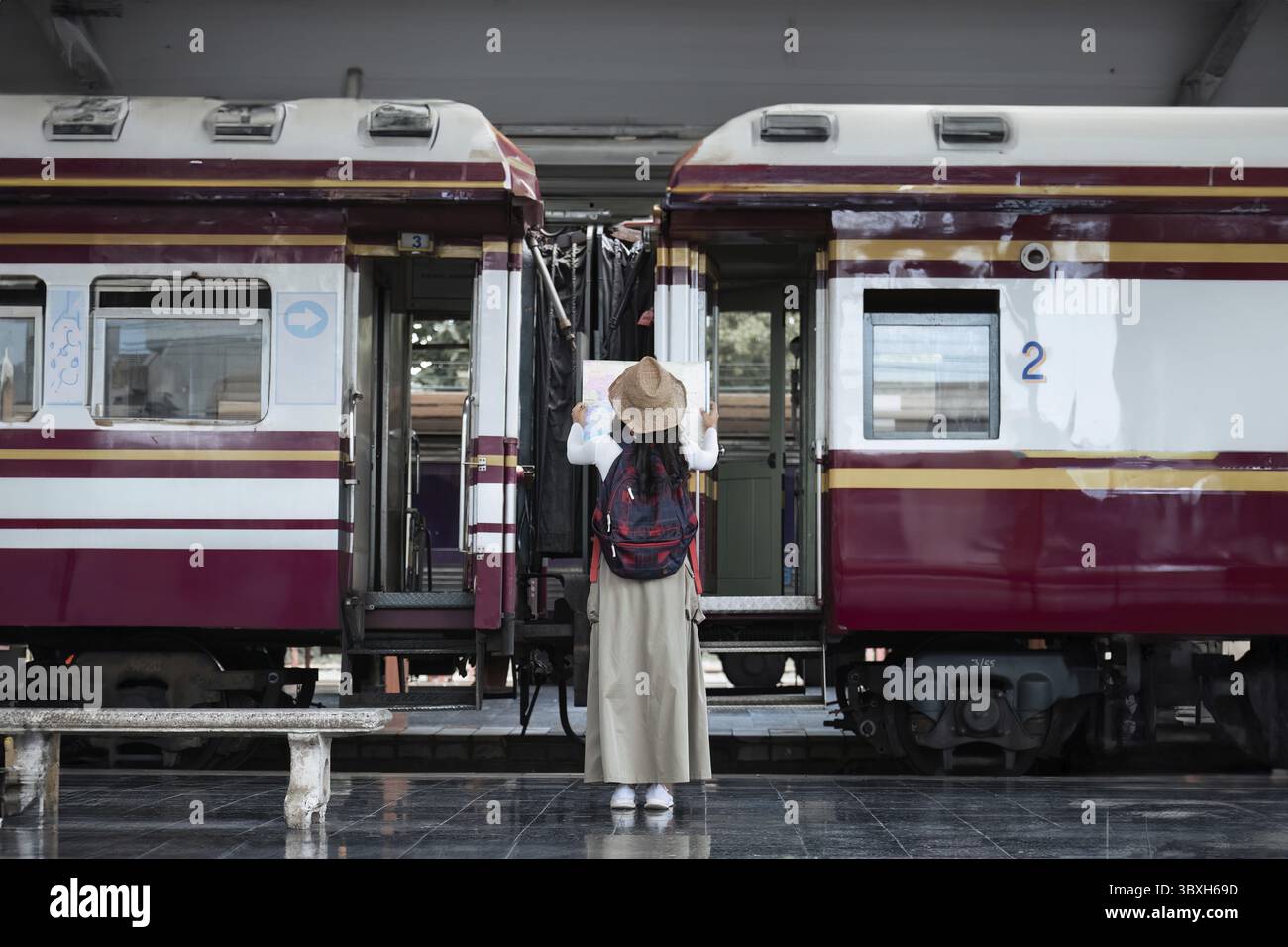 Jeune femme avec valise pour des vacances d'aventure touristique voyageant debout et regardant la carte avec un train. concept transport lifestyle actif jou Banque D'Images