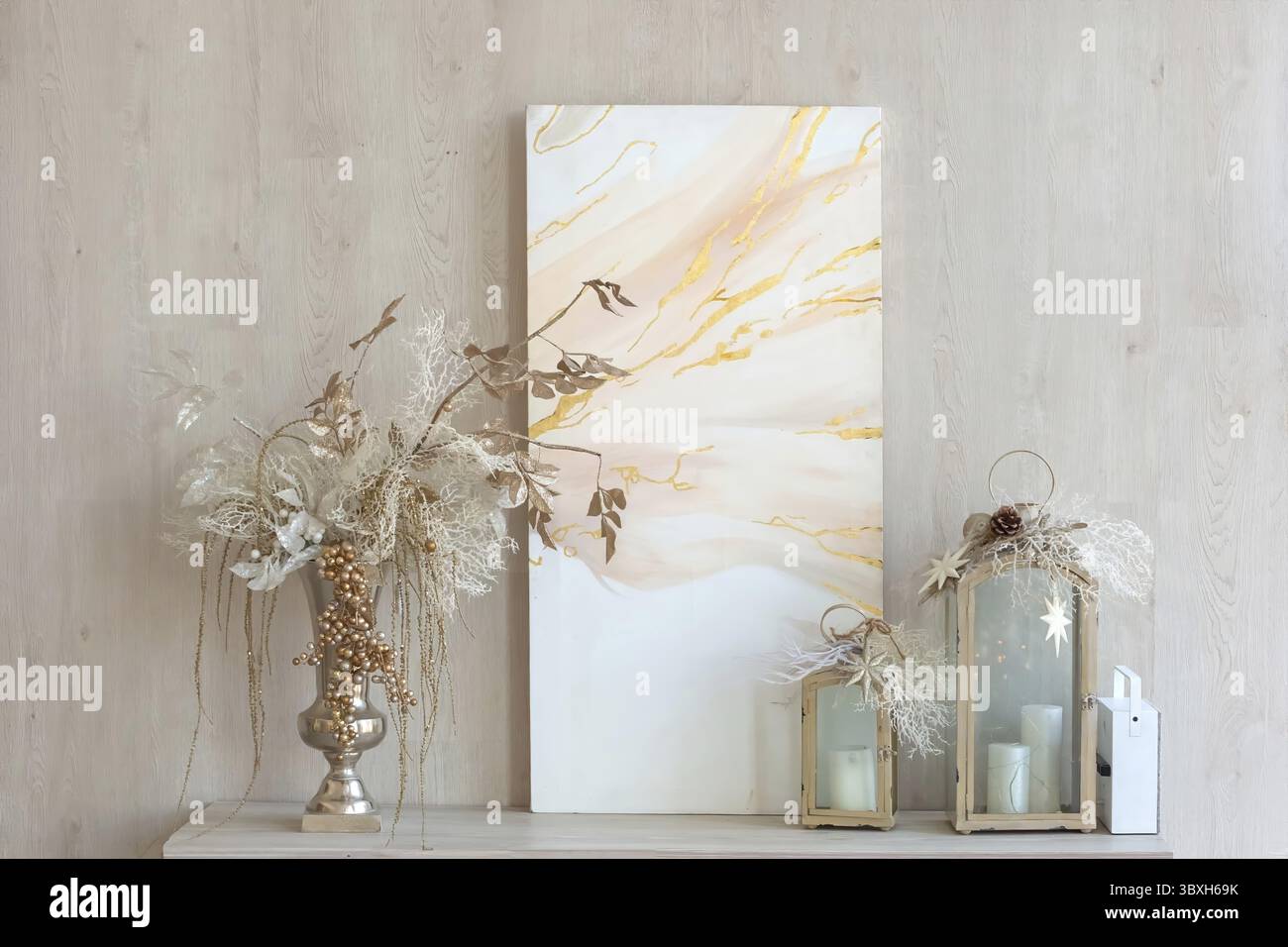 Une toile abstraite, un vase avec un décor de Noël et des lanternes décoratives avec des bougies se tiennent sur une table contre le mur. Gros plan Banque D'Images