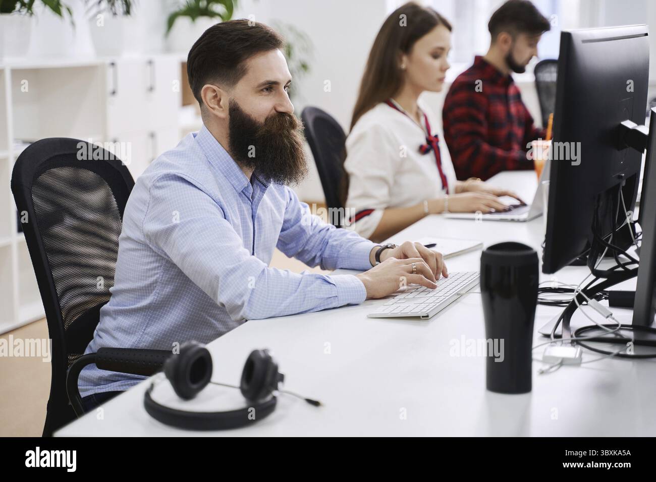 Les employés travaillant dans un bureau informatique moderne. Groupe de programmeurs et de développeurs de logiciels jeunes et expérimentés assis sur des bureaux travaillant sur des ordinateurs. Équipe à Banque D'Images
