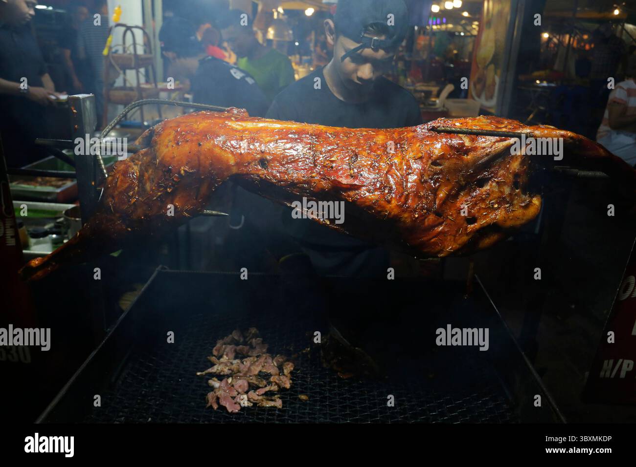 Kuala Lumpur, Malaisie - 27 novembre 2022 : un vendeur de nourriture de rue cuisine un agneau entier grillé dans la rue Jalan Alor, Bukit Bintang. Banque D'Images